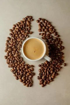 Coffee cup surrounded by roasted beans creates a warm cozy atmosphere Stock Photos