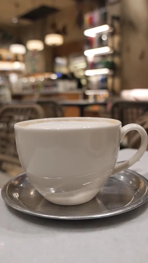 Coffee cup on a table in a cafe with blurred background in the afternoon Stock Footage 345471752