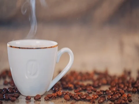Coffee cup on a  table with coffee beans. Slow motion Stock Footage 73671738