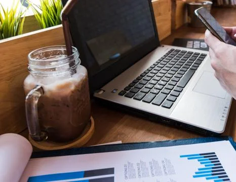 Coffee cup  on a table with laptob and graph finance diagram in coffee shop Stock Photos