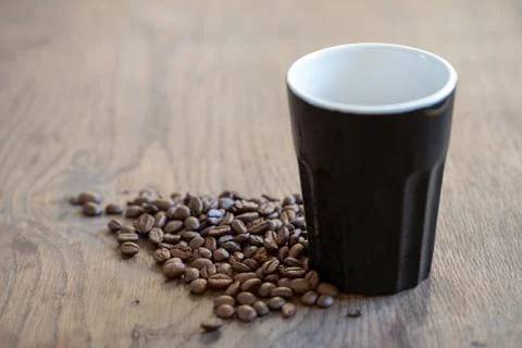 Coffee cup on table surrounded by coffee beans Stock Photos