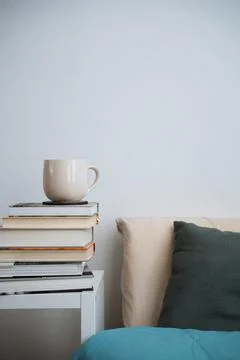 Coffee cup tea mug on stack of books next to a bed Stock Photos