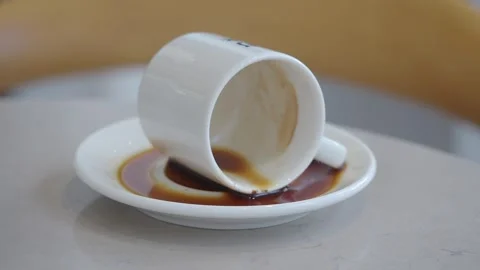 Coffee cup tipped over on a plate showing spilled coffee Stock Footage 346194167