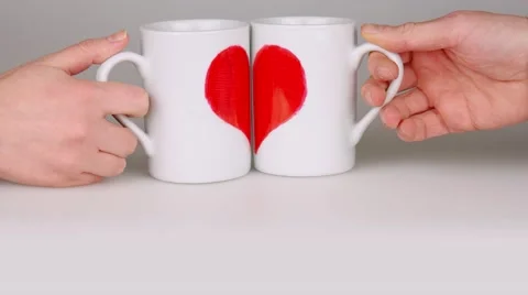Coffee cups with halves of the heart in hands unite to the one heart. Stock Footage 59532155