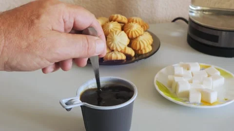 Coffee in a disposable mug on the table is stirred with a spoon Stock Footage 319578694