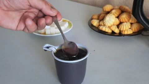 Coffee in a disposable mug on the table is stirred with a spoon. Medium shot. Stock Footage 320129686