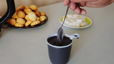 Coffee in a disposable mug on the table is stirred with a spoon. Medium shot. 動画素材 335318460