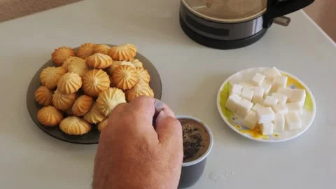 Coffee in a disposable mug on a table with sweets is stirred with a spoon Stock Footage 319954150