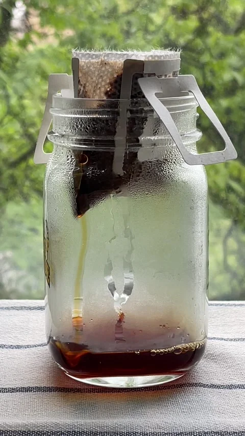 Coffee dripping from drip coffee bag filter into glass cup Stock Footage 272157879