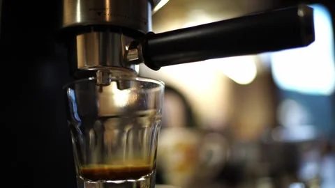 Coffee dripping from the horn of a coffee machine into a glass on a stand Stock Footage 282673122