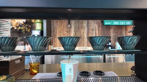Coffee drips steadily into a patterned cup through a pour-over machine. Stock Footage 333662823