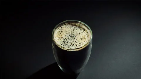 Coffee drop into the filled glass in slow motion. Stock Footage 162128613