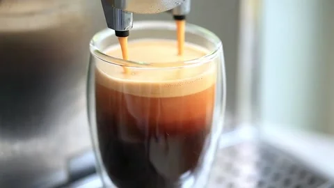 Coffee espresso streaming from coffee machine and pouring into glass. Stock Footage