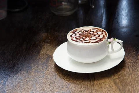 Coffee with flower pattern in a white cup on wooden background Stock-Fotos