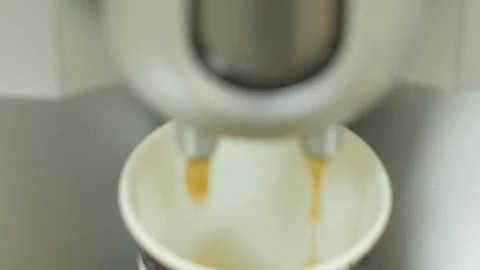 Coffee flows from the coffee machine into a paper glass. Focus on the liquid. Stock Footage 86612839