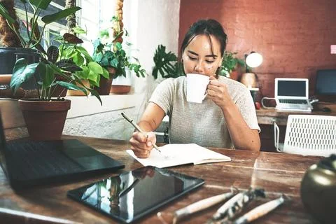 Coffee gets my creativity flowing. an attractive young businesswoman sitting in Stock Photos