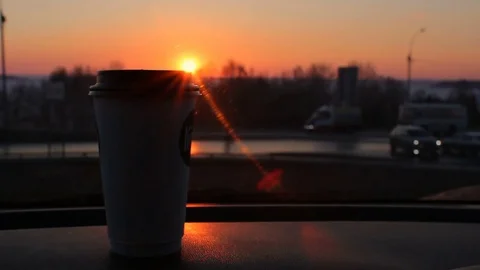 Coffee to go cup standing on car panel sunset and city road traffic background Stock Footage 75007982
