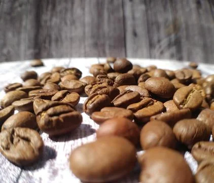 Coffee grains close-up in the rays of light on a wooden surface Stock Photos
