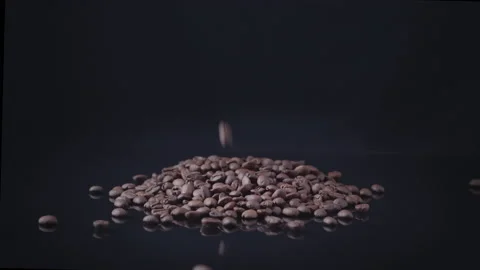 Coffee grains fall up a hill on a black background and glossy glass Stock Footage 131065247