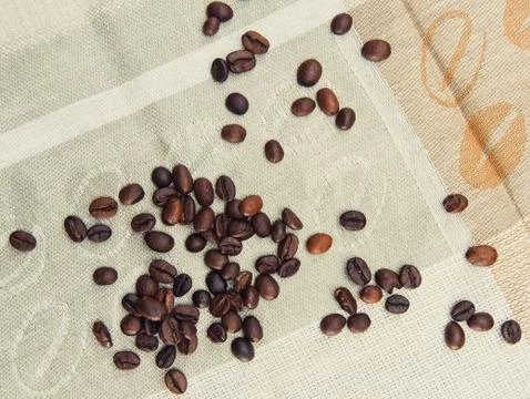 Coffee grains scattered on a patterned tablecloth Stock Photos