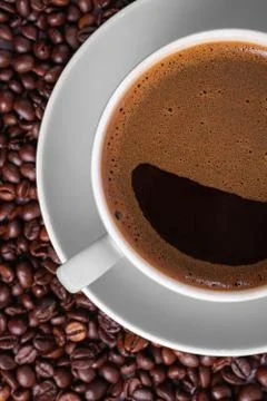 Coffee in gray cup on a table surrounded by coffee beans. Stock Photos