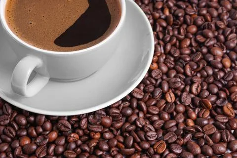 Coffee in gray cup on a table surrounded by coffee beans. Stock Photos
