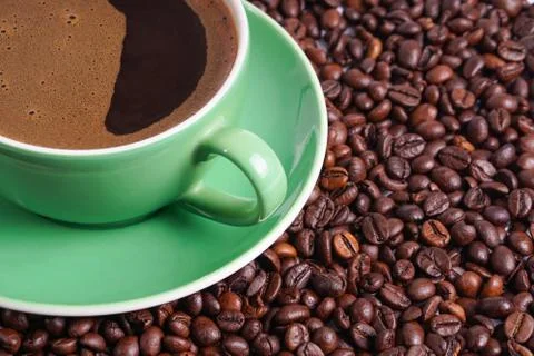 Coffee in green cup surrounded with coffee beans Stock Photos