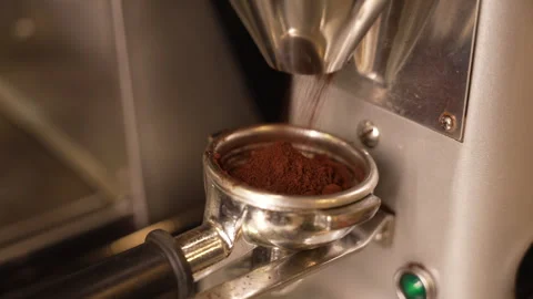 Coffee grinder dispensing freshly ground coffee beans into a metal portafilter Stock-Footage 333584000