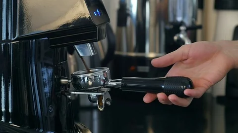 Coffee grinder grinding freshly roasted coffee beans into a coffee powder Видео 77157129