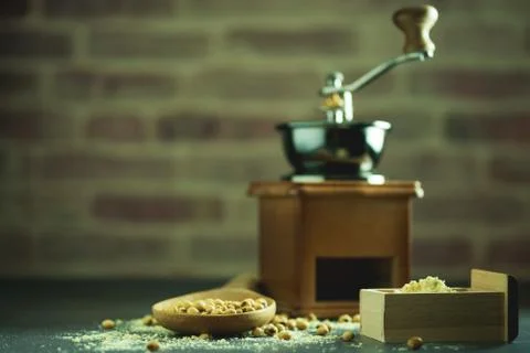 Coffee grinder grinding soybeans into powder and wooden ladle in darkness. Stock Photos