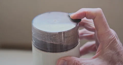 Coffee grinder grinds coffee beans into powder. Man's hand holds button on Stock Footage 240718247
