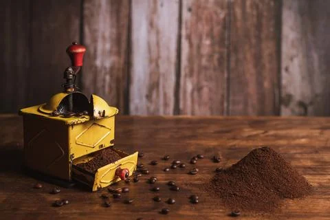 Coffee grinder next to a small mountain of ground coffee and scattered coff.. Stock Photos