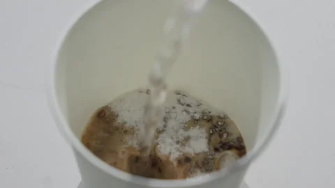 Coffee Grounds Dissolving in White Bowl Water Closeup Stock Footage 340243495