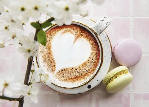 Coffee with a heart-shaped pattern and sweet macaroons desserts Foto stock