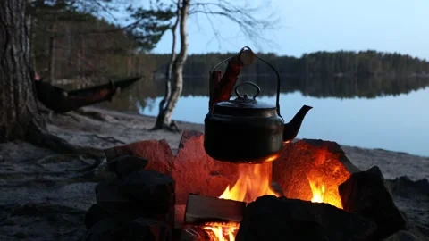 Coffee in kettle on campfire in forest on shore of lake. Stock Footage 138100294
