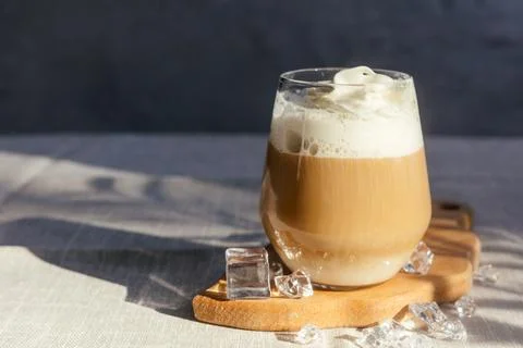 Coffee latte on a gray table in bright sunlight and free space. Cold summer.. Stock Photos