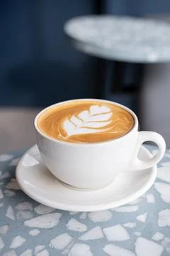 Coffee latte in a white cup inside a coffee shop, with latte art. Stock Photos