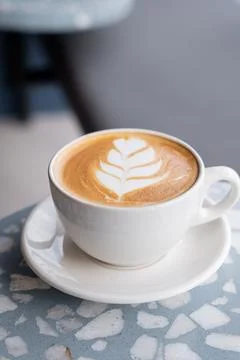 Coffee latte in a white cup inside a coffee shop, with latte art. Stock Photos