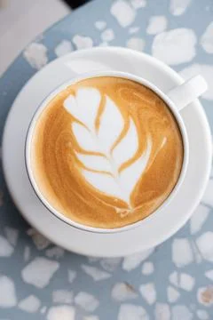 Coffee latte in a white cup inside a coffee shop, with latte art. Stock Photos