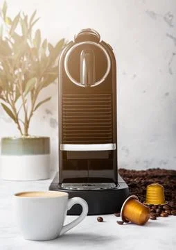 Coffee machine with cup and coffee capsules pods in light morning kitchen Stock Photos