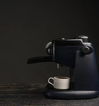 Coffee machine with a cup of coffee on a dark background Stock Photos