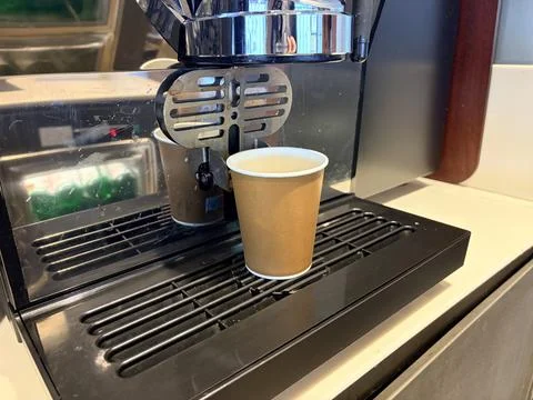 Coffee machine dispensing coffee into a paper cup. Foto stock