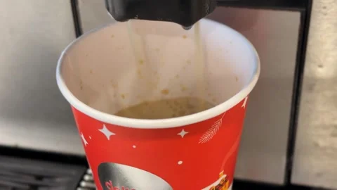 Coffee machine dispensing espresso into festive red paper cup with holiday .. Stock Footage 336398541