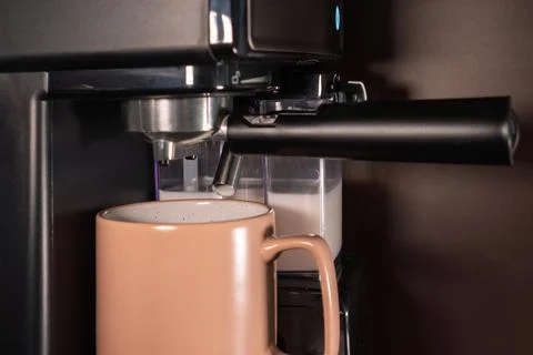 The coffee machine makes cappuccino on the kitchen table. Modern coffee mac.. Stock Photos