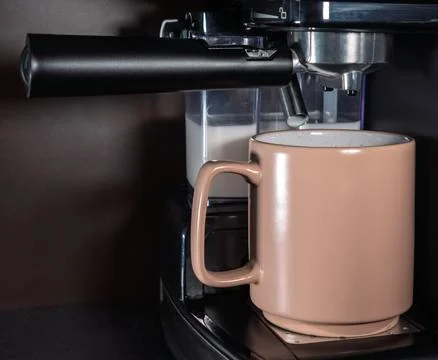 The coffee machine makes cappuccino on the kitchen table. Modern coffee mac.. Stock Photos
