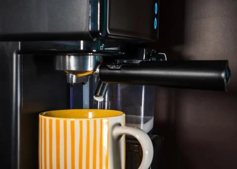 The coffee machine makes cappuccino on the kitchen table. Modern coffee mac.. Stock Photos