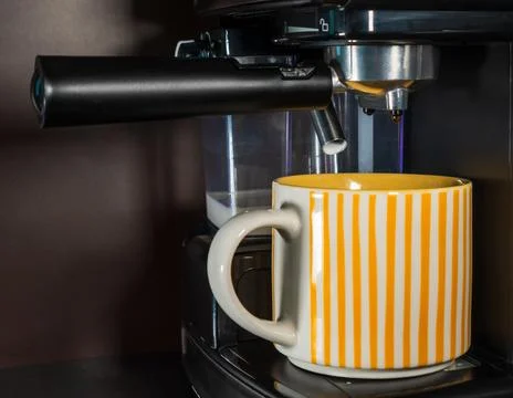 The coffee machine makes cappuccino on the kitchen table. Modern coffee mac.. Stock Photos