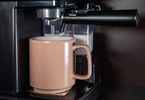 The coffee machine makes cappuccino on the kitchen table. Modern coffee mac.. Stock Photos