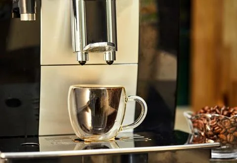 A coffee machine makes espresso in a transparent cup. Freshly brewed coffee.. Stockfoto's