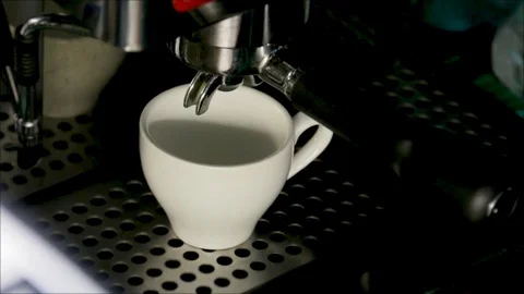 A coffee machine pouring coffee into a white coffee cup in a night bar. Hand Stock Footage 84761642